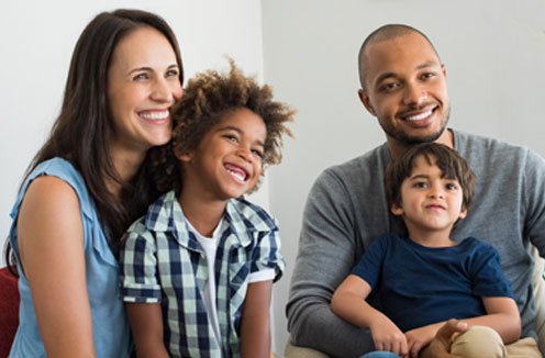 woman with child on lap sitting next to man with child on lap, all smiling