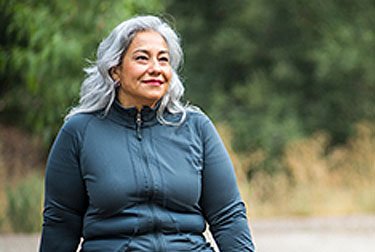 woman with gray hair in dark gray long sleeved zippered running top looking on