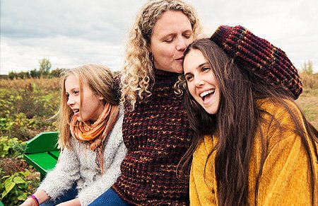 woman between two young girls kissing the top of one's head