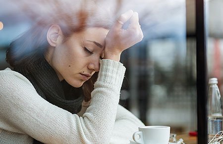 woman with head down in hand eyes closed